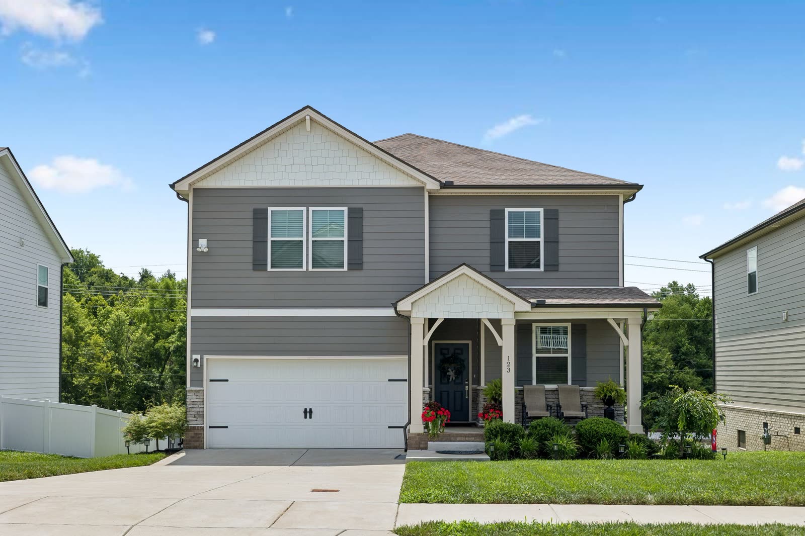 123 Millbrook Drive, a grey two-storey with stone skirt and covered front porch